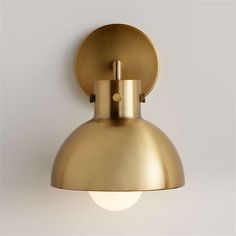 a brass wall light with a round shade on the front and back of it's head