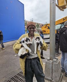 a woman holding three kittens in her hands while standing next to a street light