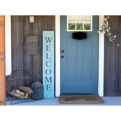 a blue front door with welcome sign and firewood on the porch next to it