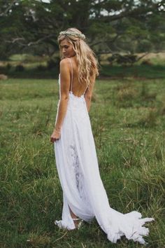 a woman standing in the grass wearing a white dress with open back and long train