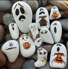 painted rocks with faces on them sitting next to some rocks in the shape of ghost and pumpkins