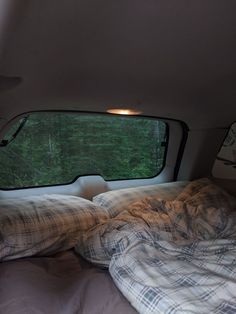 the inside of a camper with two pillows and blankets on it's bed