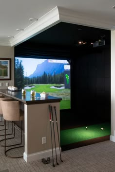 a golf simulator is set up in the middle of a room with bar stools