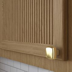 a close up of a wooden cabinet door with white tiles on the wall behind it