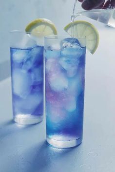 two glasses filled with blue liquid and lemon wedges