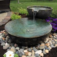 a water fountain surrounded by rocks and flowers