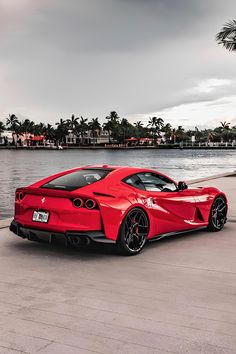 a red sports car is parked near the water