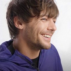 a close up of a person wearing a purple jacket and smiling at the camera with a white background