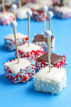 chocolate covered cake pops with white frosting and sprinkles on blue table