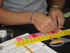 a man is measuring tape with scissors on top of a table next to some construction paper