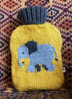 an elephant knitted hot water bottle cover sitting on top of a colorful couch cushion