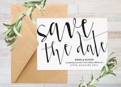 save the date card with greenery on top and envelope in brown paper next to it