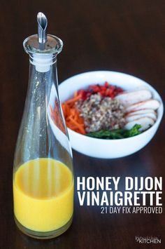 a glass bottle filled with orange juice next to a bowl of food