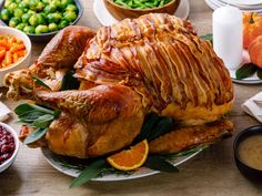 a large turkey sitting on top of a white plate next to bowls of vegetables and condiments