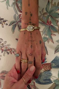 two people holding hands with tattoos and rings on their fingers, one has a diamond in the middle