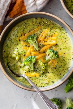 two bowls filled with broccoli and cheese soup