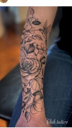 a woman's arm with flowers and leaves tattooed on the forearm, in black and white