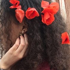 a close up of a person with long hair and flowers in her hair, holding a cell phone to her ear