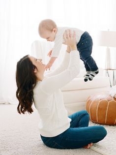 a woman holding a baby up in the air