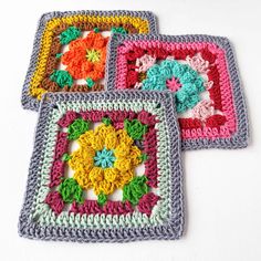 three crocheted square coasters with colorful flowers on them, all in different colors