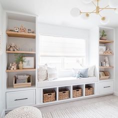 a white room with lots of shelves and baskets on the windowsill, along with some bookshelves