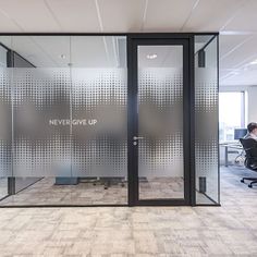 an office cubicle with privacy glass walls and two people sitting at their desks