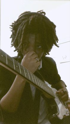 a man with dreadlocks playing an electric guitar