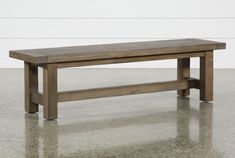 a large wooden bench sitting on top of a cement floor next to a white wall