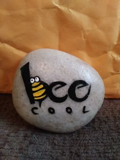 a rock with the word eco painted on it and a cartoon bee sitting on top