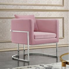 a pink chair sitting on top of a wooden floor next to a table and rug