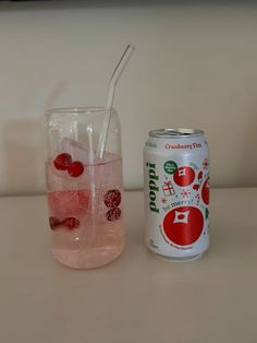 a can of soda next to a glass filled with water and cherries on the rim