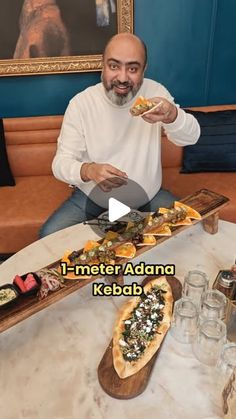 a man sitting at a table with food in front of him and the caption reads i - meter adnan kebab