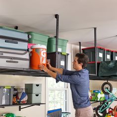 a man is hanging out in the garage with several storage bins on the ceiling