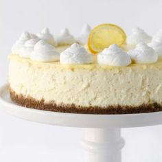 a white cake with lemon on top and whipped cream around the edges is sitting on a pedestal