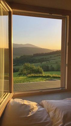 a bed sitting under a window next to a lush green field