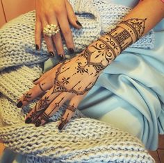 a woman's hand with henna tattoos on it