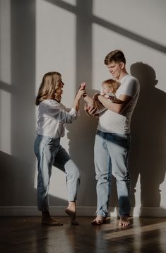 a man and woman standing next to each other in front of a wall holding hands