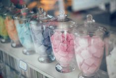 there are many different colored candies in glass jars