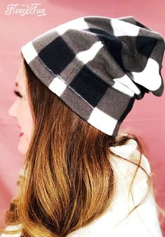 a woman wearing a black and white checkered hat with long hair in front of a pink background