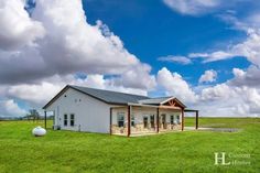 a large white house sitting on top of a lush green field under a blue cloudy sky