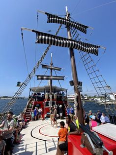 people are sitting on the deck of a boat with an elaborately decorated mast and ladders