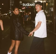 a man and woman holding hands on the street