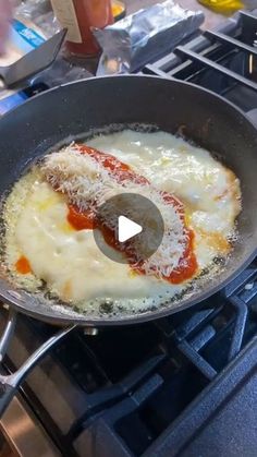 a frying pan filled with cheese and sauce on top of a stove burner