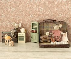 two stuffed animals sitting in a suitcase next to a wallpapered room with flowers on the walls