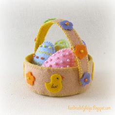 a felt basket filled with easter eggs and decorated peep - poop balls, on a white background