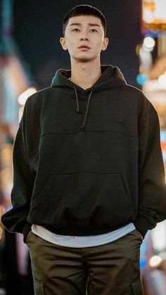 a young man standing in the street wearing a black sweatshirt and khaki pants