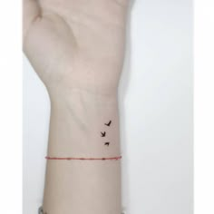 a person's wrist with two birds on it and a red string attached to the wrist