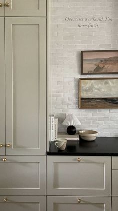 a kitchen with white cabinets and black counter tops in front of a painting on the wall