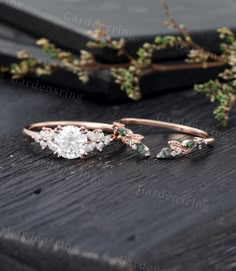 two rose gold rings with green and white stones are sitting on top of a wooden table