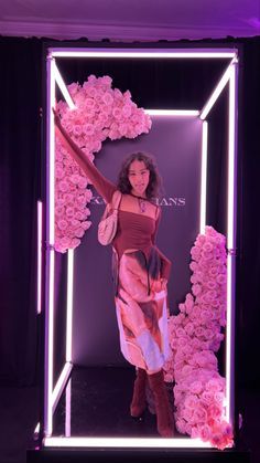 a woman standing in front of a display with pink flowers